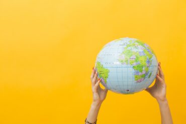 Communication glocale : un globe sur un fond jaune, tenu par des mains