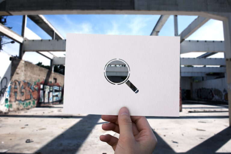 Paysage industriel caché par une page blanche où est détourée une loupe