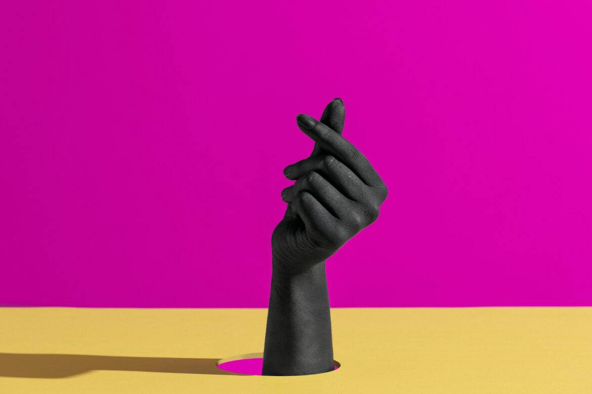 fond coloré, jaune et mauve, avec une main, peinte en noir qui sort du décor