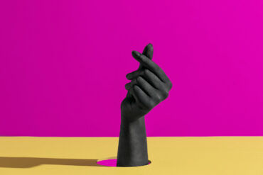 fond coloré, jaune et mauve, avec une main, peinte en noir qui sort du décor